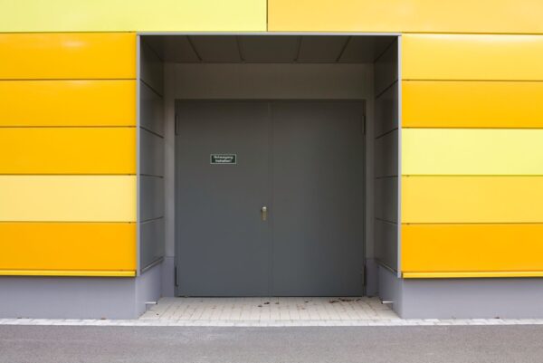 A set of double doors that lead into a building with bright yellow patterned siding.